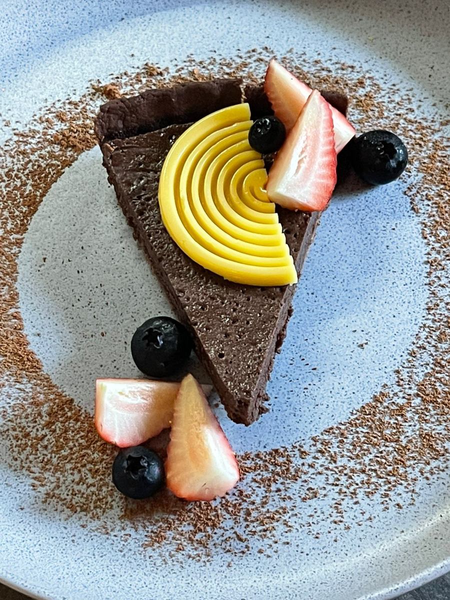 Rebanada de tarta de chocolate con mousse de maracuyá, fresas y moras