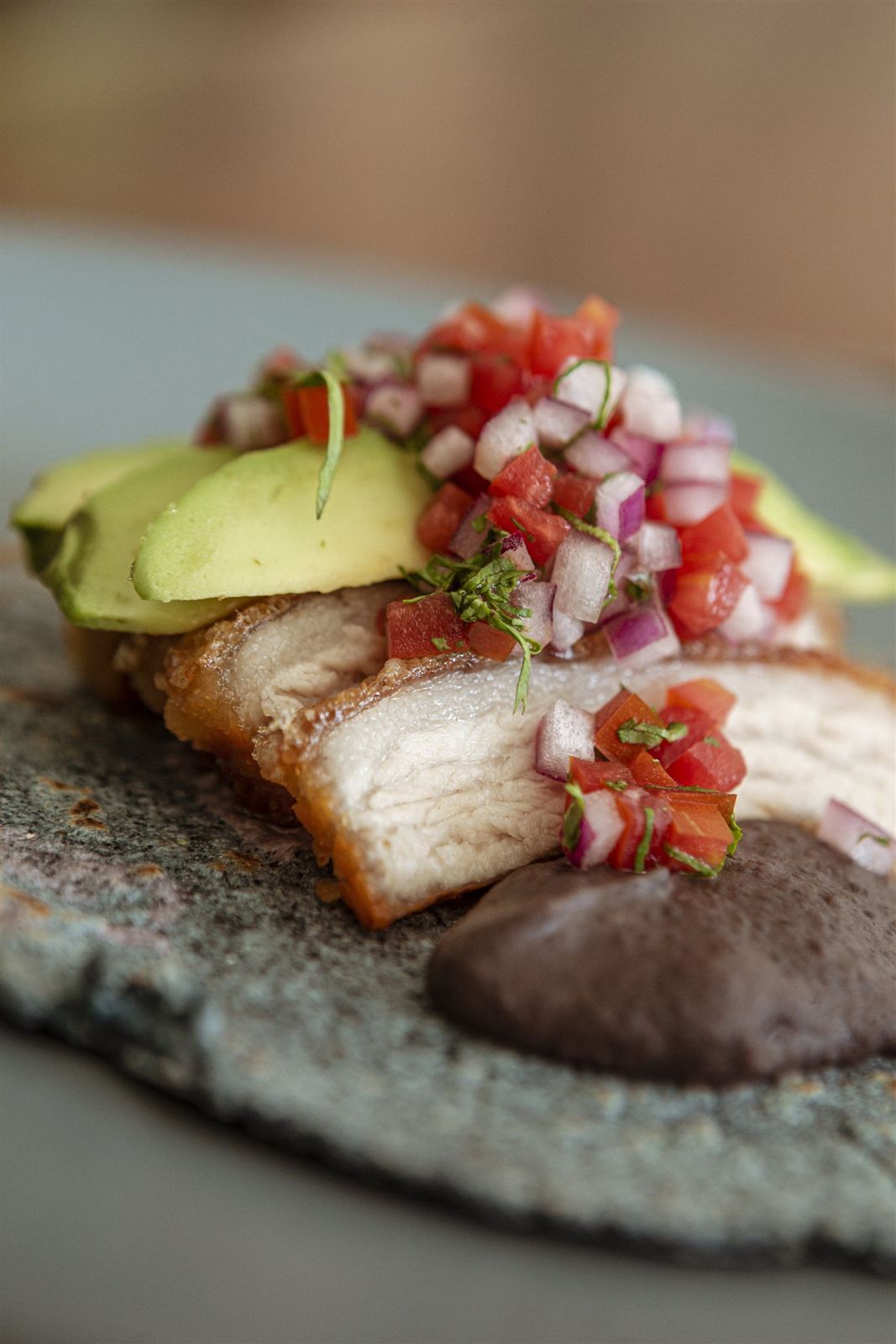 Tortilla con chicharrón, salsa y granada sobre piedra